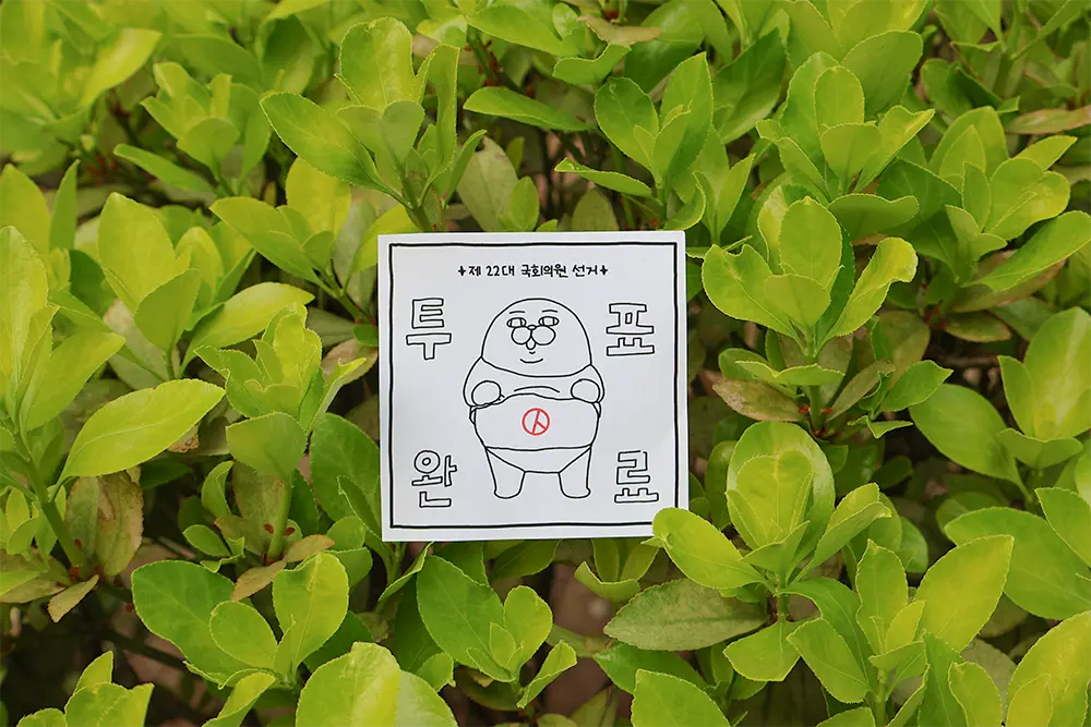 연두색의-푸릇하고-풍성한-잎사귀들-가운데-인증-종이가-한가운데-놓여있다