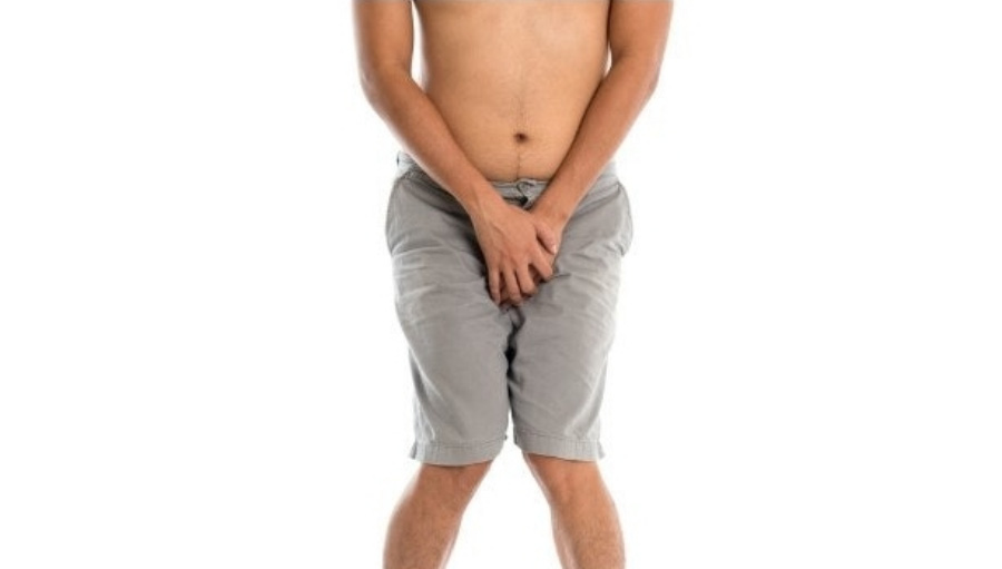 상의를 탈의하고 회색의 반바지를 입고 있는 남성이 양쪽 손으로 사타구리를 감싸며 낭습으로 고생하고 있는 것을 표현하고 있는 것을 찍은 사진