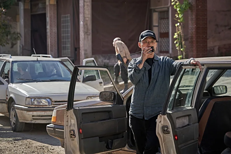 비공식작전 김성훈 영화감독이 자동차 문을 열고 서면서 무전을 하고 있는 모습