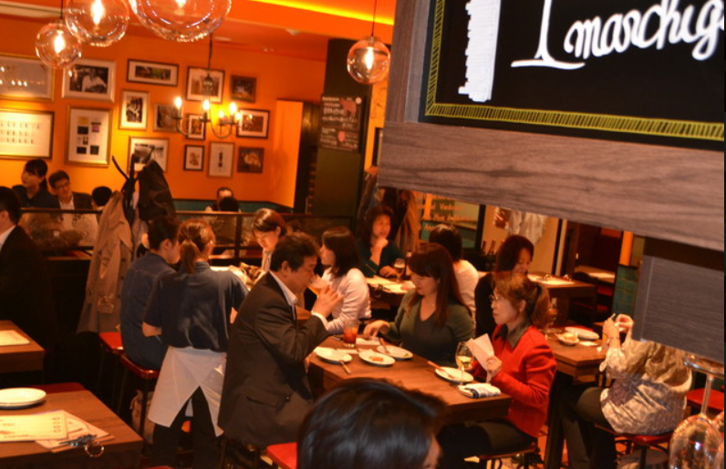 식당 내부에서 여러 사람들이 음식과 술을 마시고 있다.