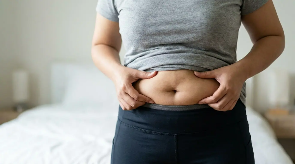 다이어트를 했지만, 살이 탄력이 없어 처진 뱃살을 만지고 있는 여성