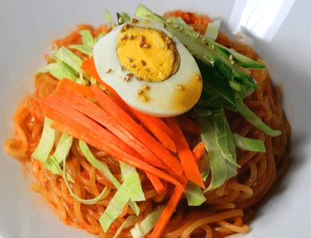 매콤한 쫄면 위에 당근채, 오이채, 삶은 달걀 반 개가 얹어있다.