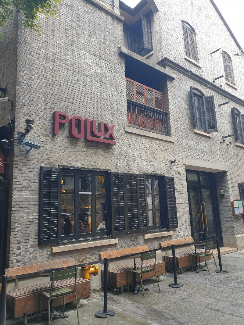 회색 벽돌 건물에 붉은색 POLUX 간판이 인상적인 곳