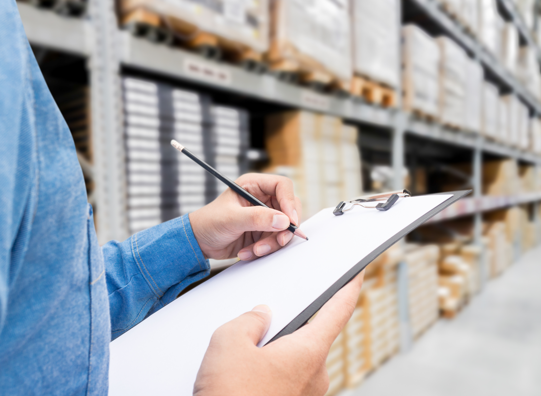 직원이 창고에서 입고와 출고한 자재를 A4용지에 적고있다.