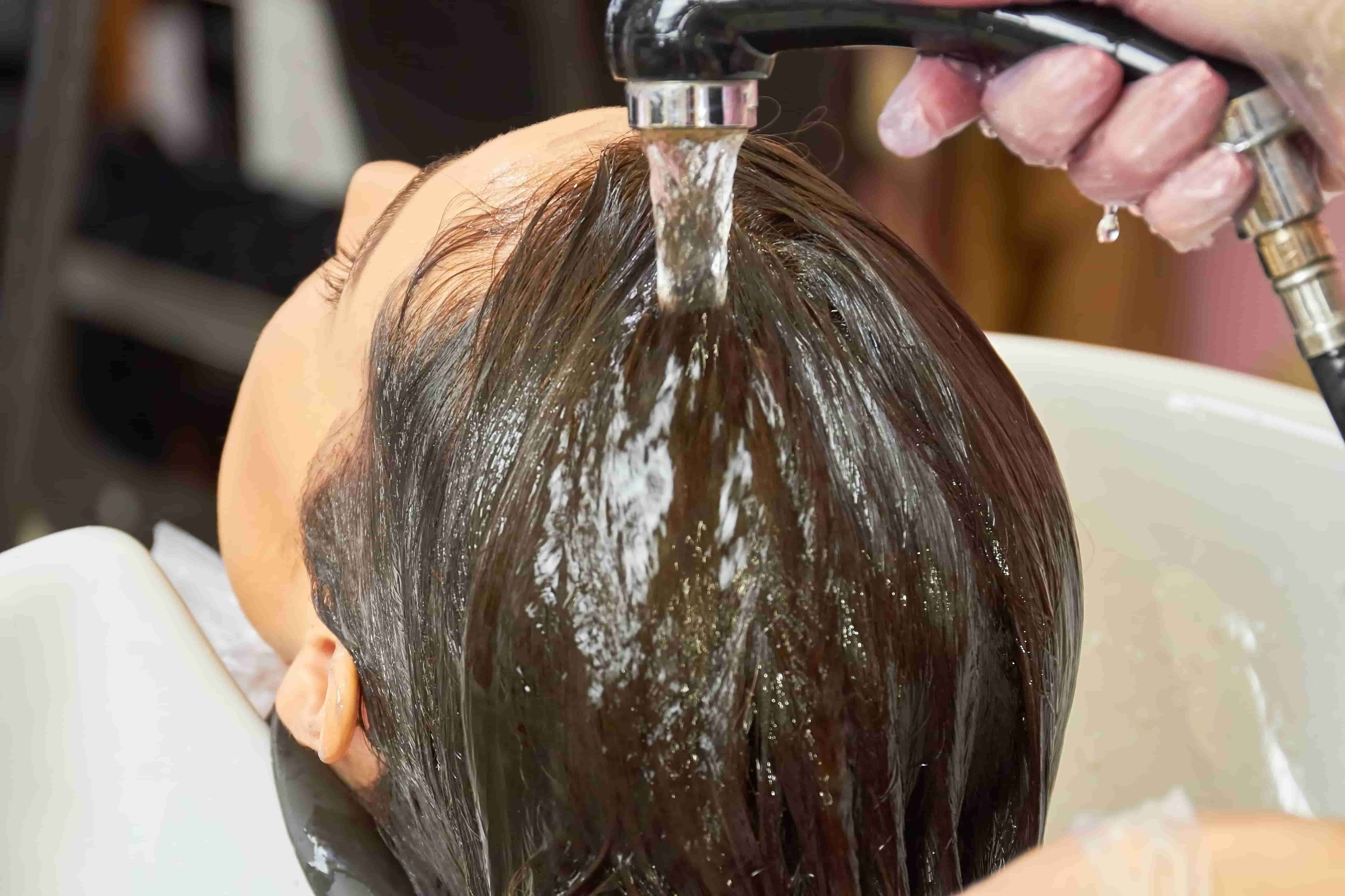 미용사가 여성의 머리를 감겨주고 있다.