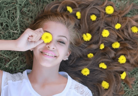 잔디 위에 한 백인 소녀가 누워 있다. 곱슬기가 있는 긴 갈색머리에 노란 꽃들이 20개 뿌려져있고 오른 손으로 노란 꽃 한개를 오른 눈에 갖다댔다.