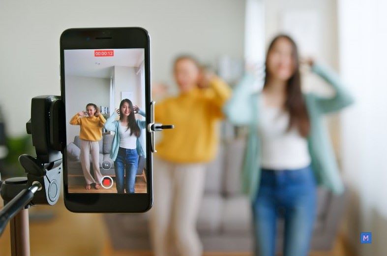 틱톡 영상 촬영 중인 두 명의 크리에이터, 스마트폰으로 댄스 콘텐츠를 제작하는 모습 via Canva