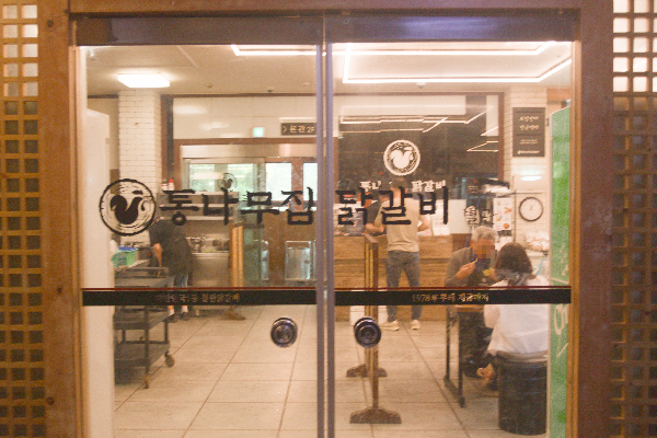 2층 별관 자동문 앞. 문 너머 앉아서 먹고 있는 사람들이 보인다.
