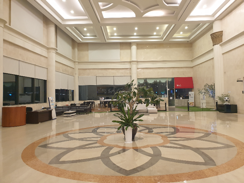 넓은 로비 중앙에 화분이 있다. 그 뒤쪽에는 의자들이 있다.