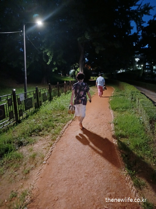 야간에 황토길 맨발 걷기를 하며 면역력과 피로 회복 효과를 체험하는 사람