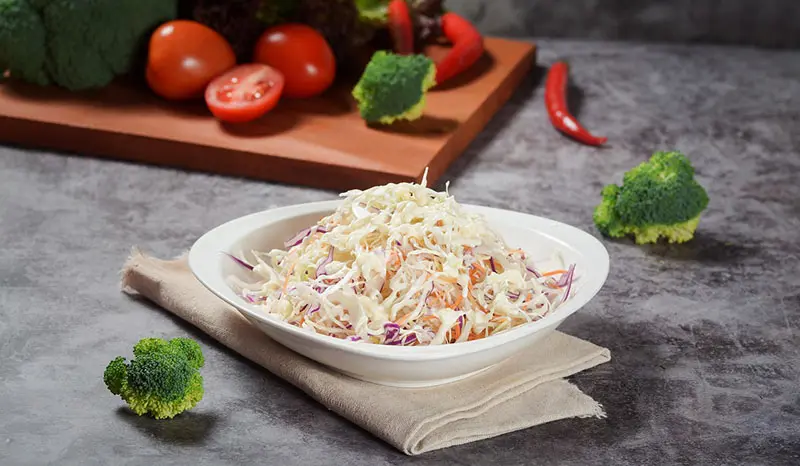 채 썰어 만든 양배추 샐러드와 주변에는 브로콜리, 방울 토마토가 놓인 이미지.