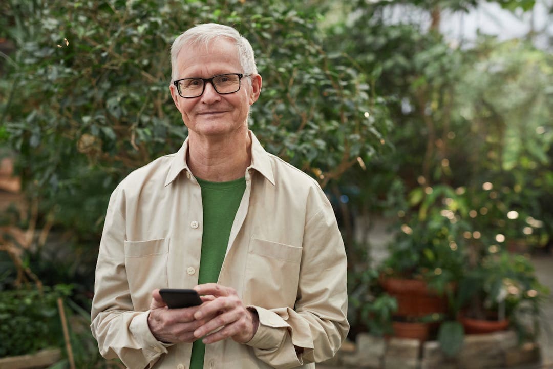 자연 속에서 스마트폰을 들고 미소 짓는 노년 남성