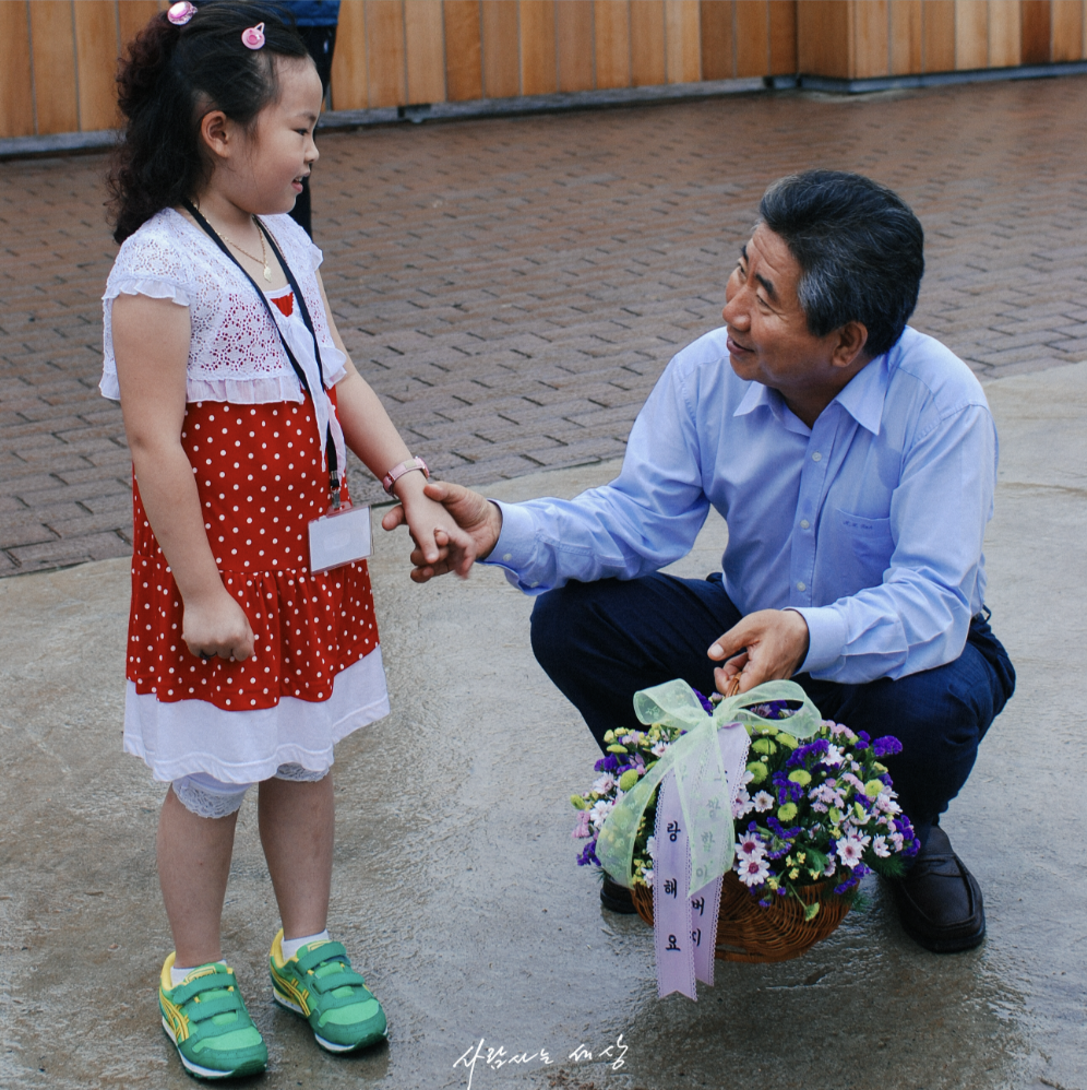 고 노무현 대통령이 어린 아이의 손을 잡아주는 사진입니다.