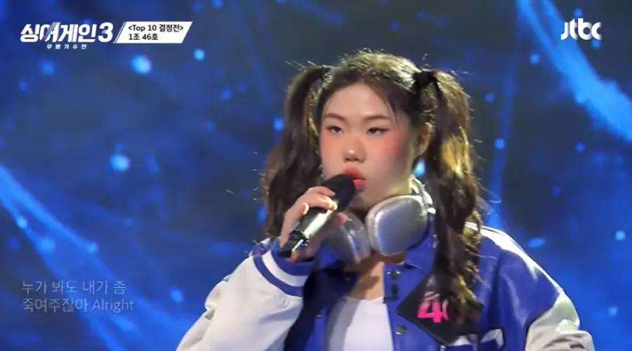 싱어게인3-
붉은 무대조명 청바지야 파란잠바를 입고 머리를 양갈래로 묵고 검정색 마이크를 들고 노래하는 46호의 왼쪽 얼굴