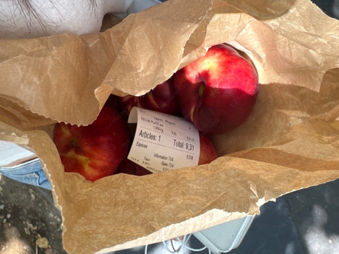 A close-up shot of a juicy donut peach cut in half, revealing the soft white flesh and small pit