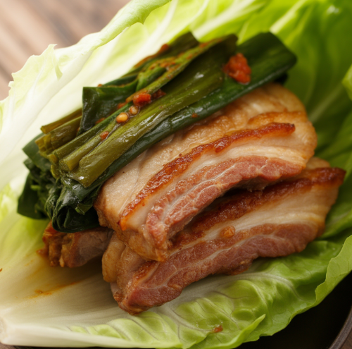 삼겹살 위에 파김치를 얹은 쌈 싸기 완성 사진, 고기 기름이 반짝이는 클로즈업