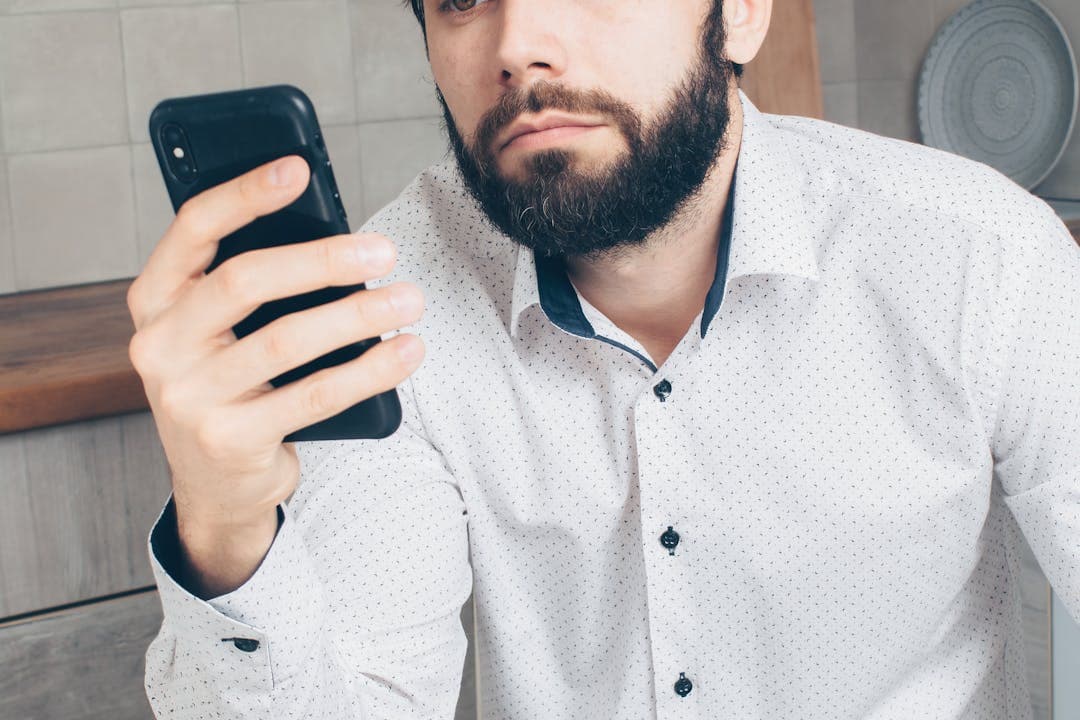 스마트폰을 응시하는 남성, 보이스피싱 의심 문자 확인 중인 모습
