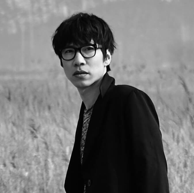 짙은-잘-지내자-우리-짙은이-검은-뿔테-안경을-끼고-검은-재킷을-입고-있는-흑백-사진