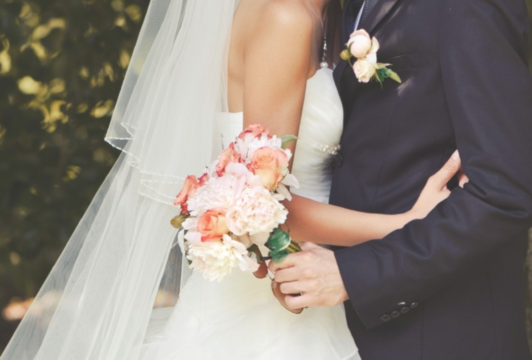 부케를 든 신랑이 신부와 포옹하는 모습