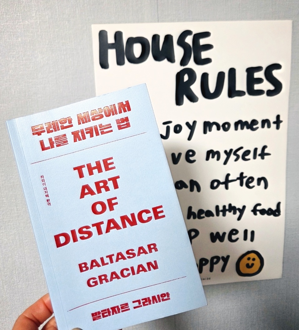 무례한 세상에서 나를 지키는 법 책을 손에 들고 있는 모습, 뒤에 HOUSE RULES 인테리어 보드