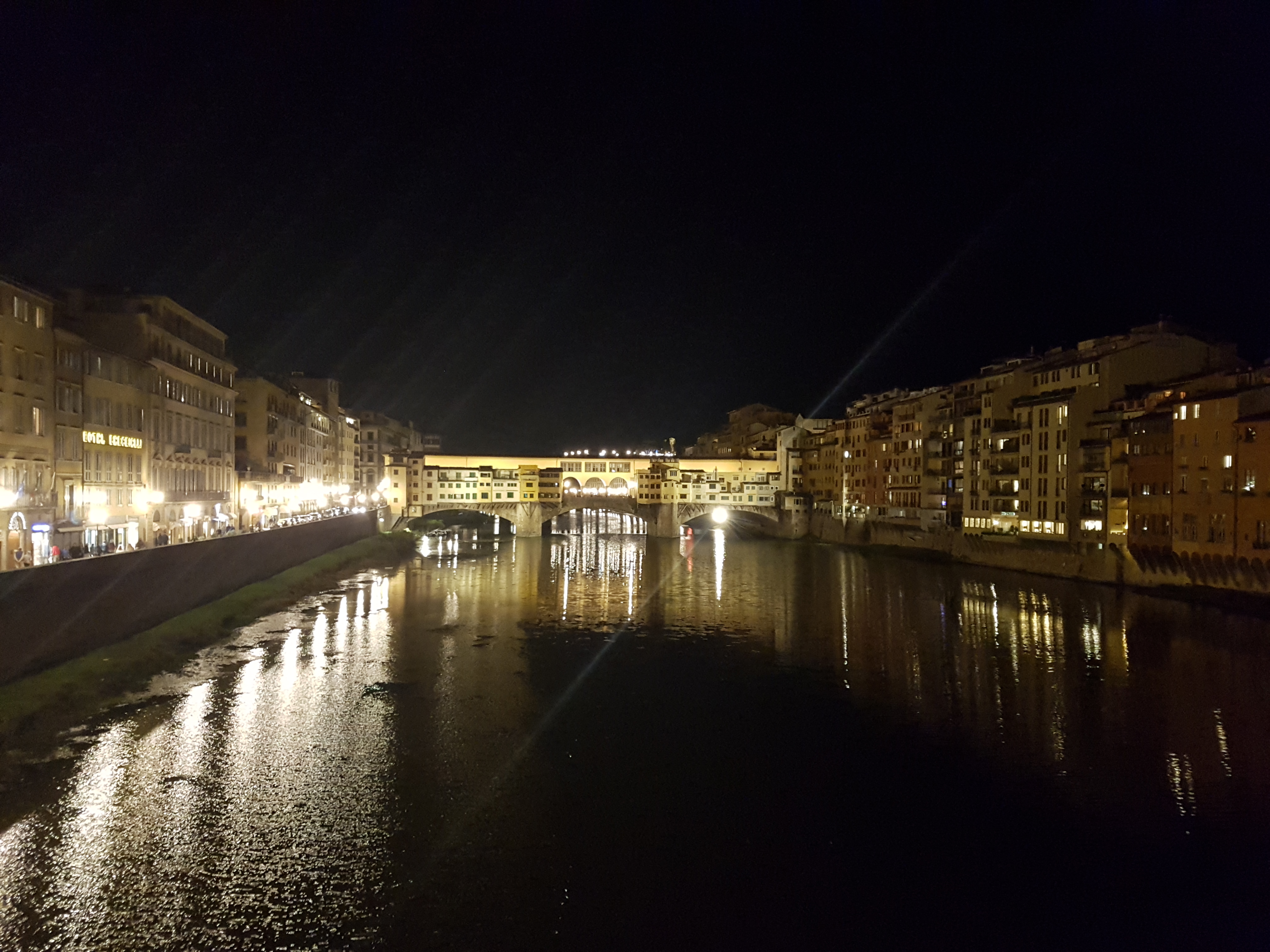 아르노 강 위로 화려한 조명이 비치는 밤의 베키오 다리 풍경
