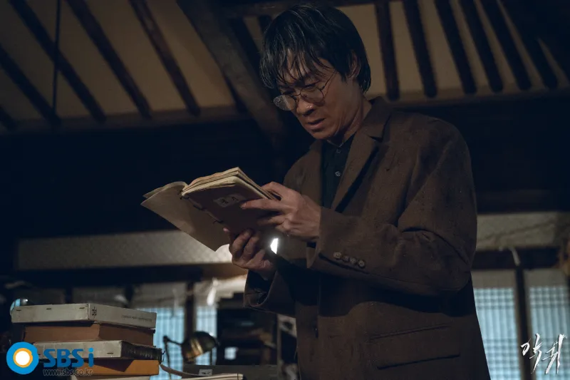 한 전통가옥에서 오래된 고서를 심각한 얼굴로 펼치면서 보고 있는 구산영의 아버지인 구강모