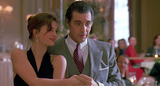 영화 '여인의 향기' 속 알 파치노가 아름다운 여성과 탱고를 추는 상징적인 장면. 춤추는 두 사람의 모습과 주변의 사람들.