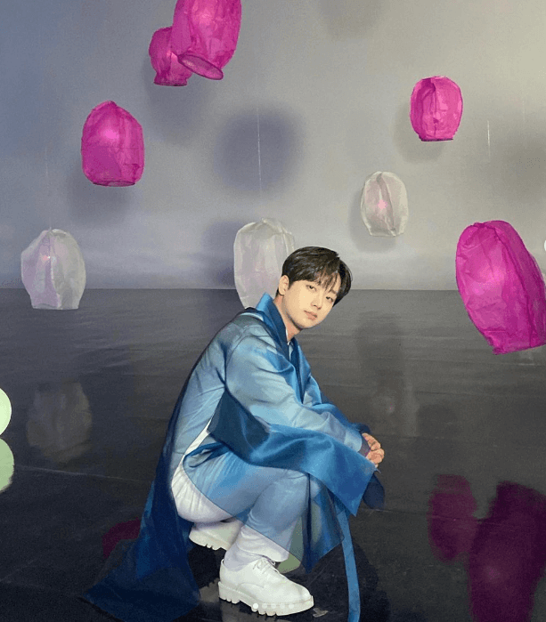 이찬원이 파란옷을 입고 쪼그려 앉아 사진을 찍고 있는 장면