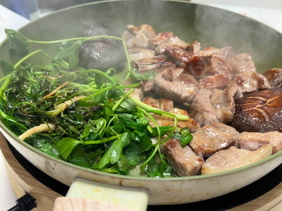 후라이팬에 미나리, 냉이, 목살, 버섯이 구워지고 있다