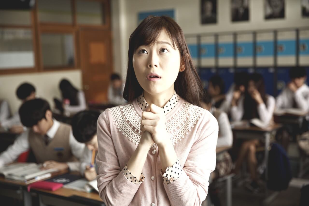 담임선생님이 TV 속 만복이를 응원하며 두손을 꼭 모으고 있는 모습