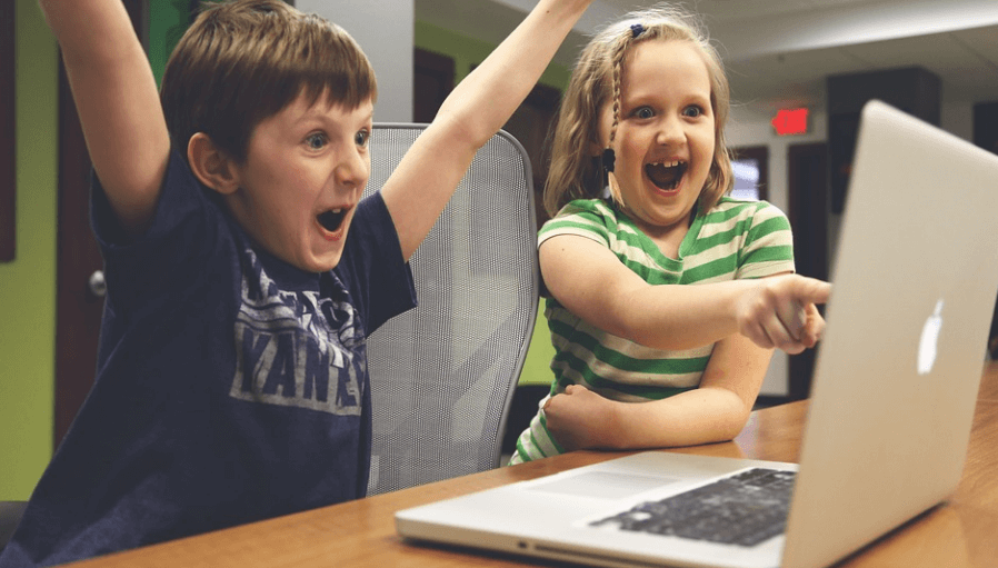 가리비 효능은 성장기 어린이에게 도움이 된다. 노트북을 보며 환호하고 있는 남자 여자 어린이