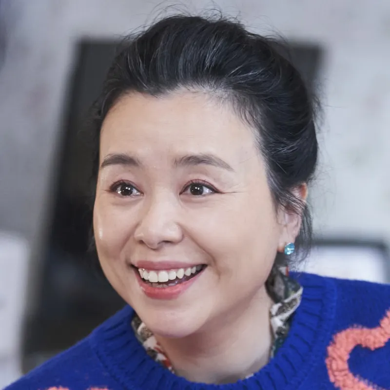 어느 실내를 배경으로 올백에 파랑 옷을 입고 웃고 있는 오랫동안 당신을 기다렸습니다의 홍영희