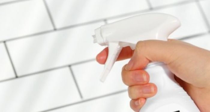 타일 벽면에 곰팡이 제거제를 뿌리는 손. 욕실이나 주방 곰팡이 제거를 표현한 이미지