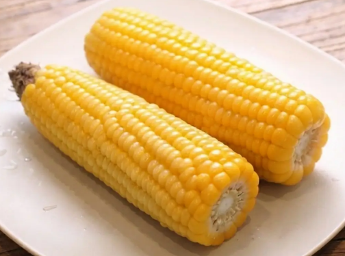 삶은 옥수수 2개가 접시 위에 놓여 있음.