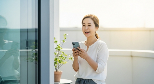 테라스에서 스마트폰을 들고 웃고 있는 중년 여성