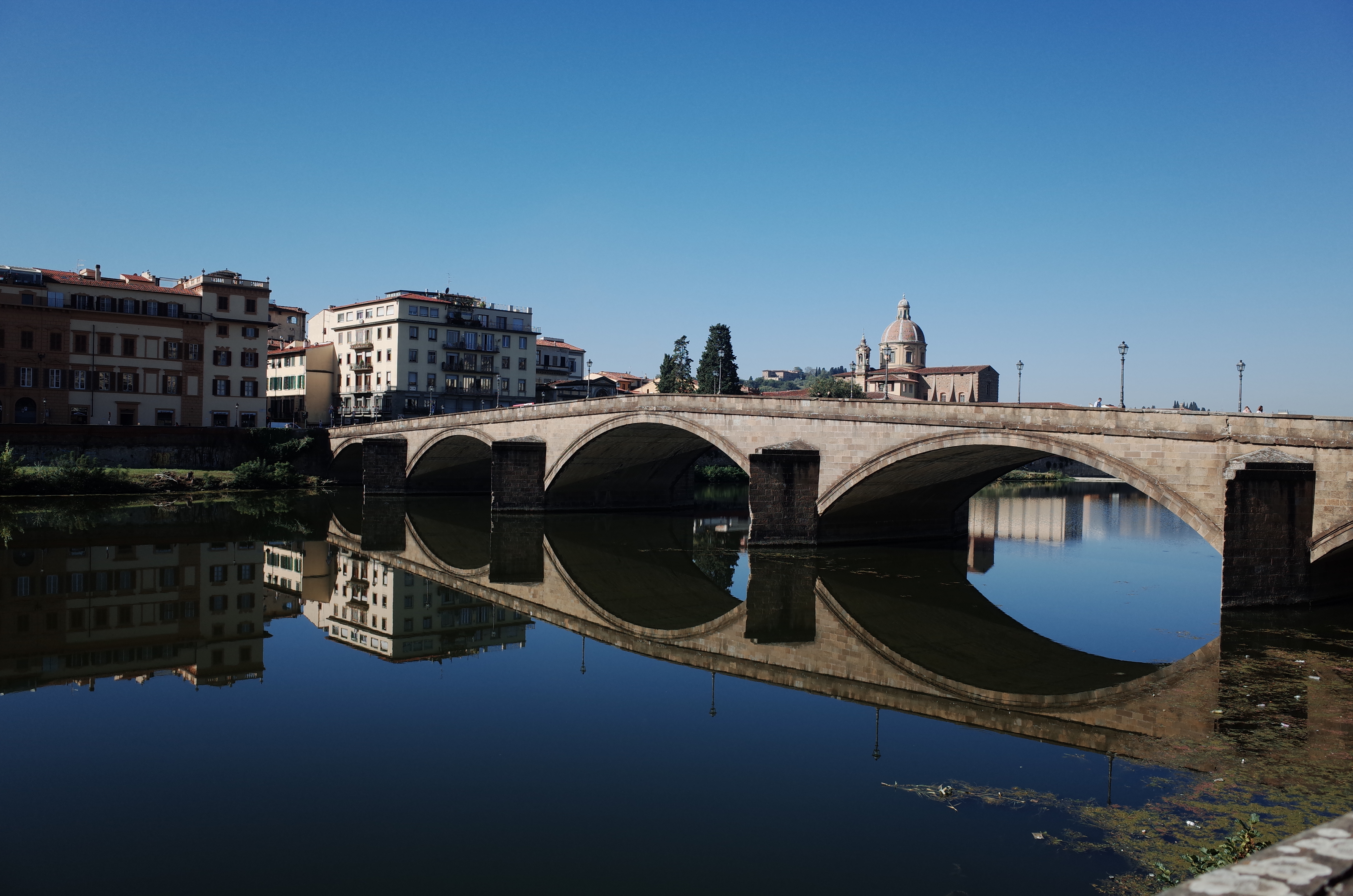 맑은 날씨의 피렌체 아르노 강과 강물에 대칭으로 투영된 산 트리니타 다리의 풍경