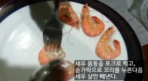 포크로 새우 몸통 살을 찍고 숟가락으로 꼬리를 누른 후 살을 빼낸다