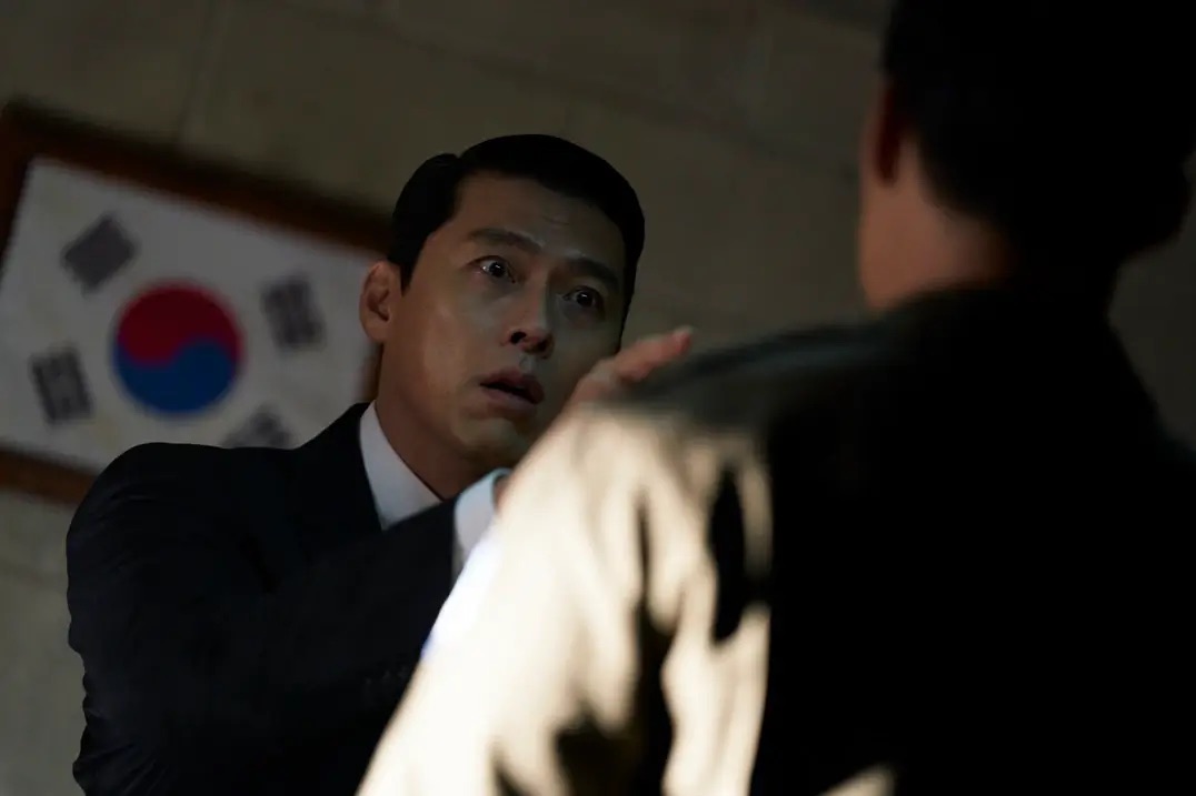 태극기를 배경으로 동생에게 손가락질 하며 눈이 커진 백기태
