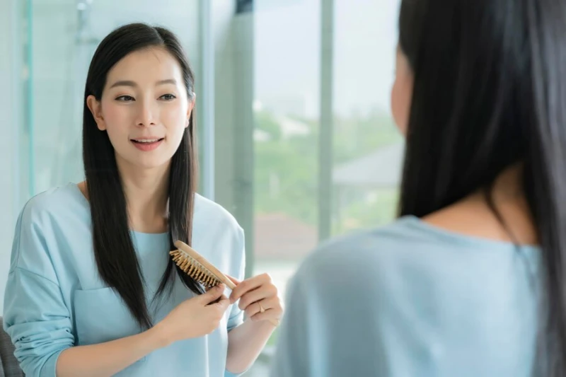 머리결이 건강한 머리를 빗질하고 있는 여성