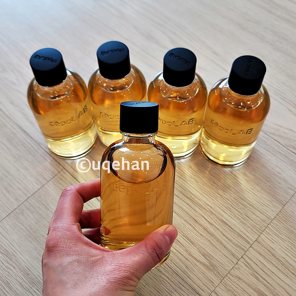 바닥에 세포랩 바이오제닉 에센스 4병이 있고 손으로 1병을 들고있다.