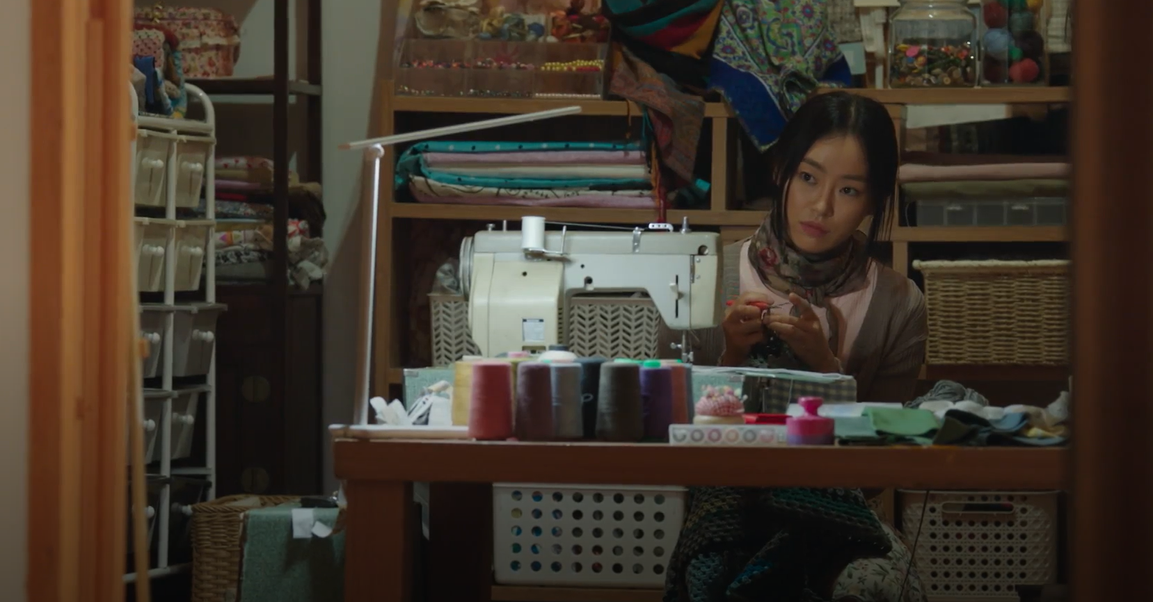 혼자 방 안에 앉아 수선하는 카야의 장면(언어&middot;체류&middot;고립의 압박)