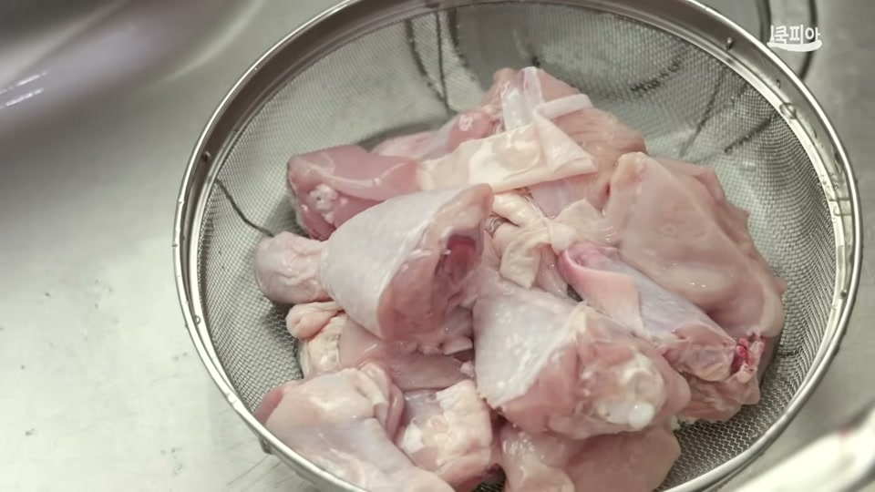 굵은소금으로 닭을 씻어 체에 밭치는 장면