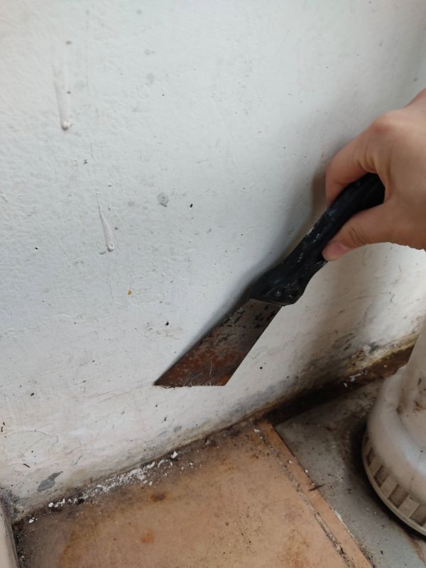 부서지는 벽면 페인트를 긁어내고있는사진