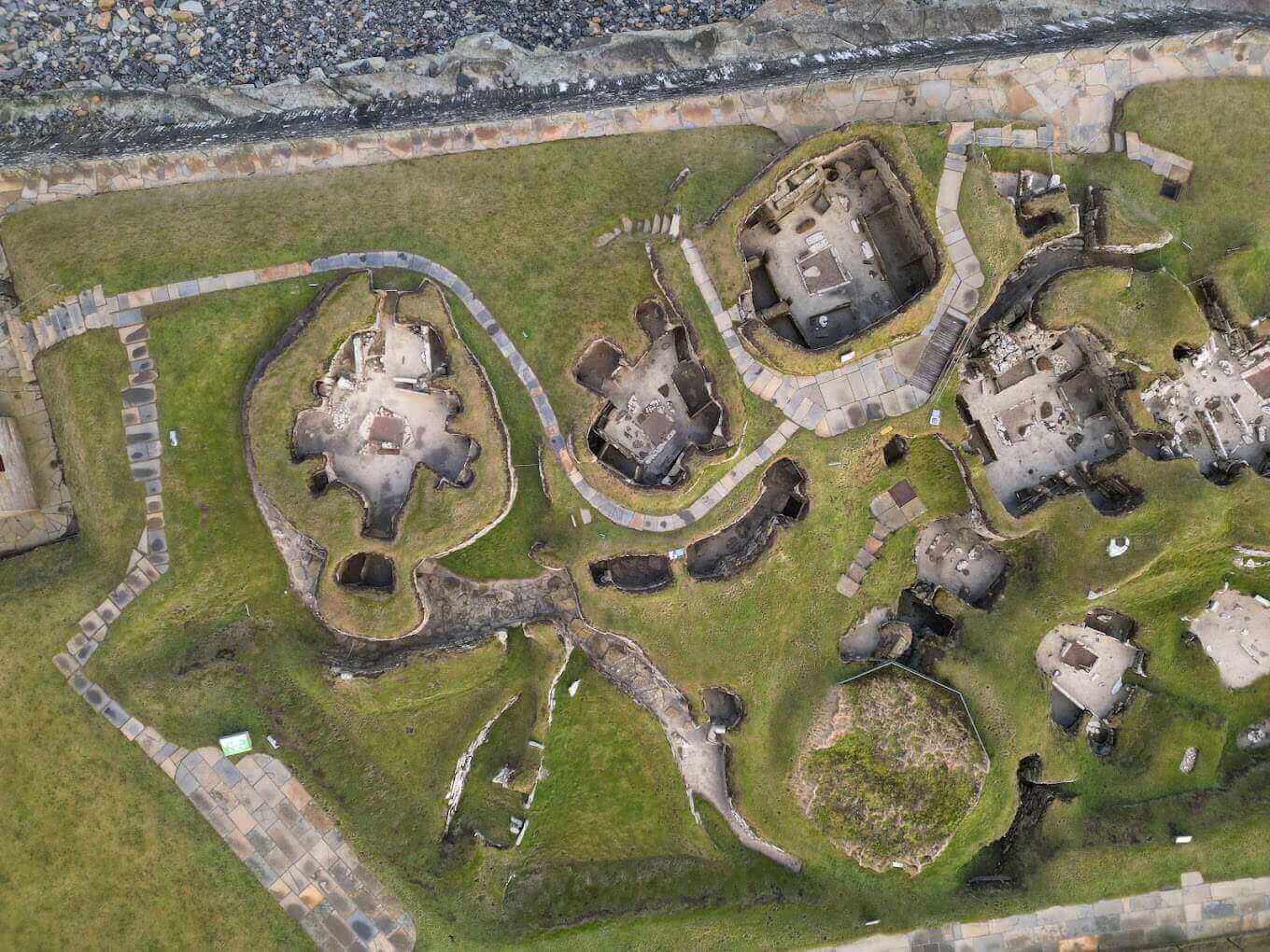 스코틀랜드 스카라 브레이 유적의 항공 사진으로, 원형의 석조 주거지들이 초지 위에 연결되어 있다.