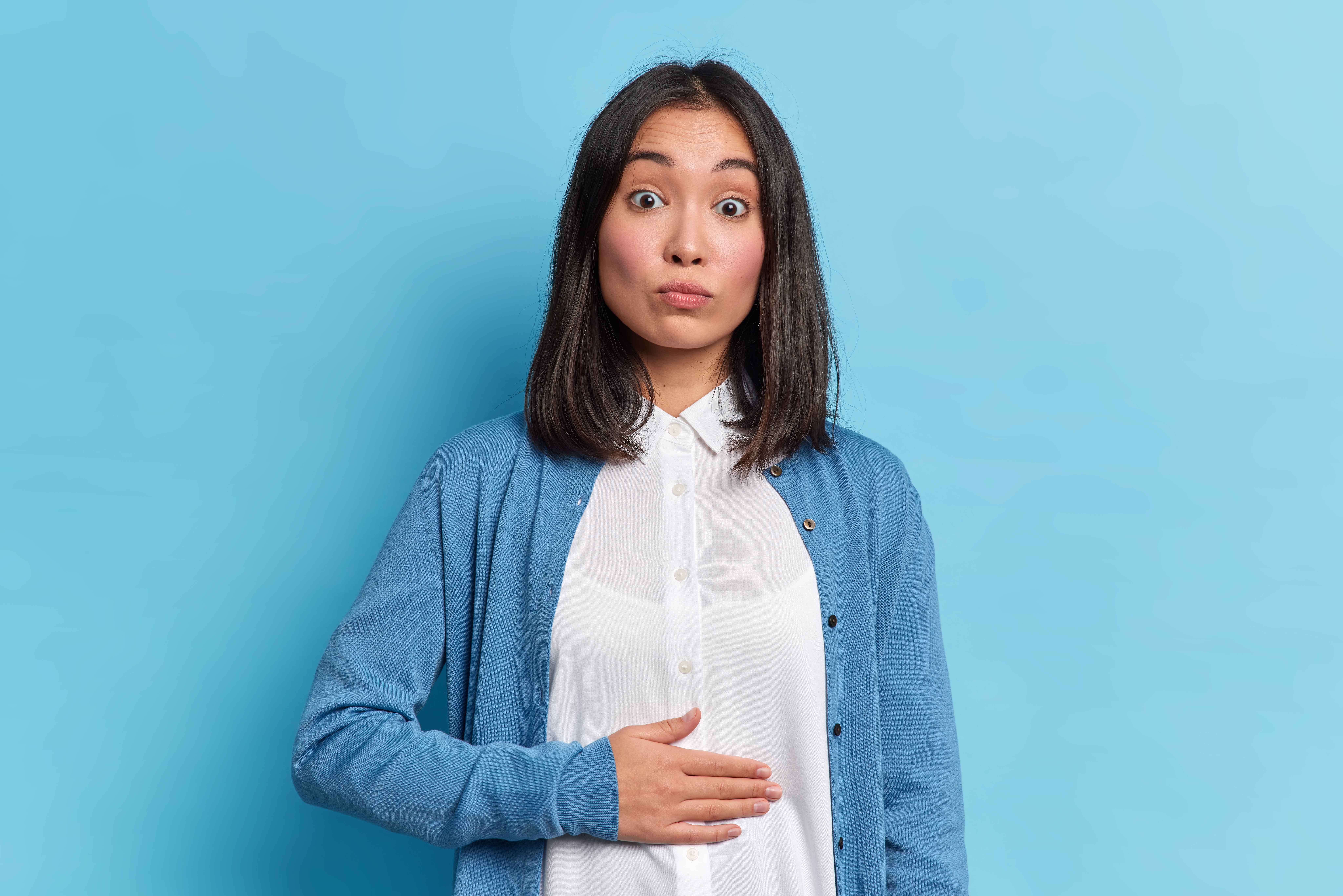 속을 어루만지며 놀란 표정을 짓는 여자