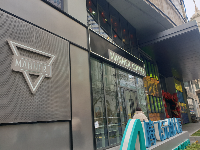 회색 메탈 바탕 프레임에 검은색 간판을 한 매너커피