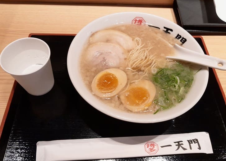 검은색 쟁반 위에 라멘 물 그리고 나무 젓가락이 올라가 있다.