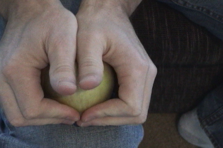 두 손으로 사과를 움켜쥐고 쪼개려 하는 사진