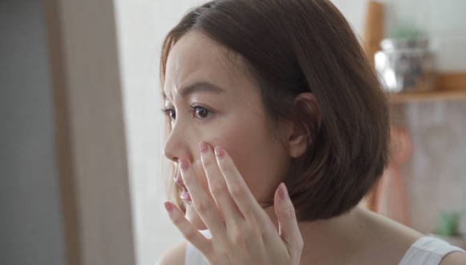 얼굴만지면서 인상쓰는 여성 사진