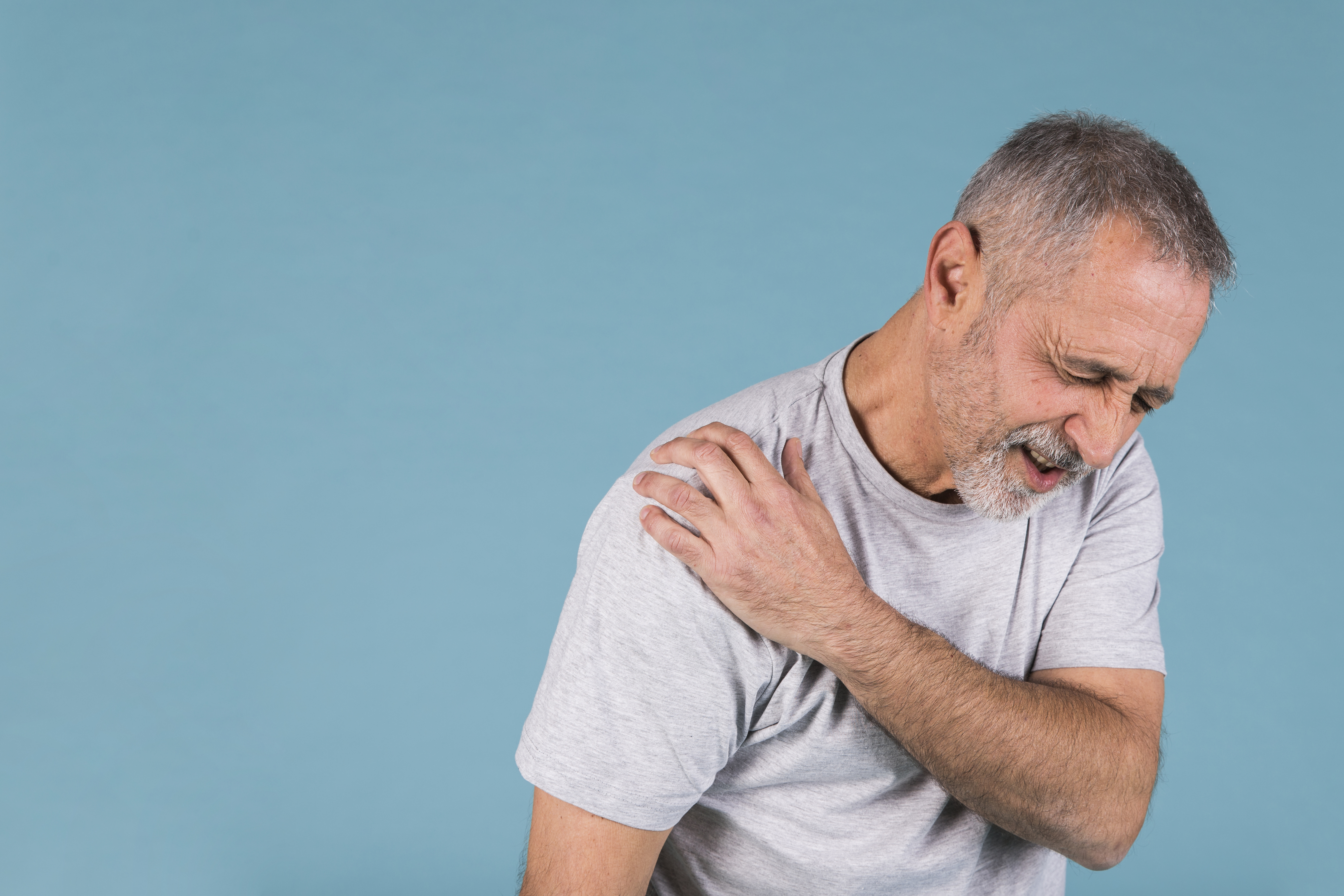 어깨 통증 (stressed-senior-man-with-shoulder-pain-blue-backdrop)